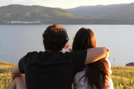 Loving couple on top of the mountain. Embrace. Sunset. A young girl with long hair and her...