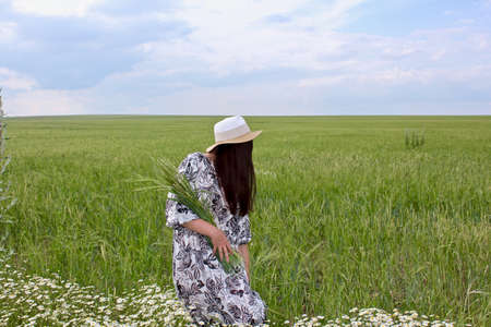 A young lucky girl in a blossoming field picking wildflowers.の写真素材