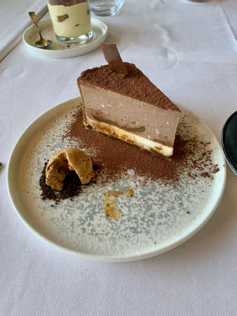 A piece of chocco cake on a plate next to a cup of coffeeの写真素材