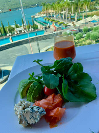 A white plate of healthy food on a table, Healthy food clean eating selection: Avocado Arugula Cherry Salmon Cheese, Vegan dinner eatingの写真素材