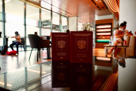 Passports to world travel. Travel design. Two red passports is on the table is ready for check-in in the lounge of airport. Two Russian passports on the background of the airport loungeの写真素材