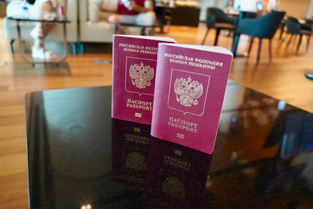 Passports to world travel. Travel design. Two red passports is on the table is ready for check-in in the lounge of airport. Two Russian passports on the background of the airport loungeの写真素材