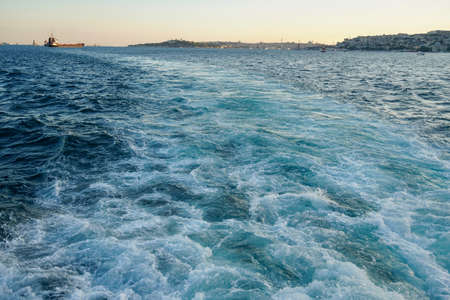 Bubbling blue waves of traces of tourist cruise ships passing on the Bosporus. Water trail foaming behind a passenger ferry boat in Bosphorus, Istanbul, Turkey.の写真素材