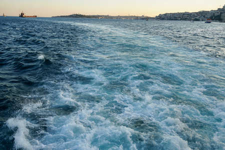 Bubbling blue waves of traces of tourist cruise ships passing on the Bosporus. Water trail foaming behind a passenger ferry boat in Bosphorus, Istanbul, Turkey.の写真素材