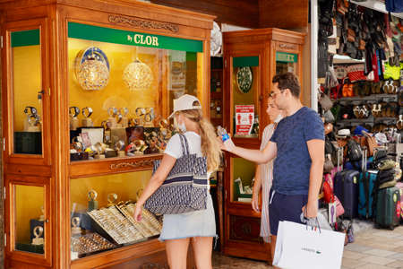 Bodrum, Turkey - August, 2020: View of the city street with stores. Tourists buy souvenirs from the local Turkish market. Young people are looking at the showcase with the goodsのeditorial素材