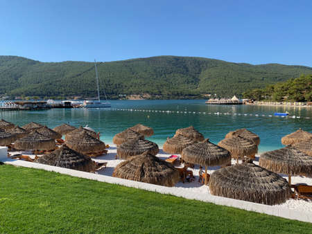 Parasol on the tropical beach with white sand, evergreen hills, snow-white yachts. Luxury conceptionの写真素材