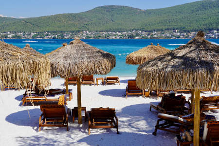 Snow-white beach of Lux Hotel with emerald water of Aegean Sea. Sunbeds on the beach. Relaxing Deluxe Leisure Conception. High quality photoの写真素材