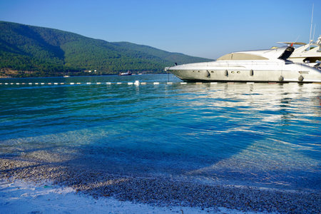 Panorama of sandy beach with beautiful rocks, palms and a sailing boat in the turquoise sea on...