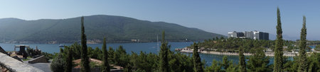 Panoramic amazing view landscape. Picturesque morning view of popular Turkey destination - Bodrum, lagoon Aegean sea. Amazing summer seascape of Aegean sea. Beauty of nature concept background. White boats and green hills background. Cypress trees in the foregroundの写真素材