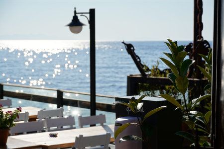 Outdoor cafe with a chic view of the bay, Seaside wooden table and chairs open cafe outdoor restaurant in Marina Bay, Bodrum -Turkey on sea shore. Summer vacation on resort.の写真素材