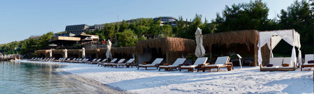 Panorama view with palm trees, white sand and bamboo parasols. Luxury tropical island with over water villas and blue lagoon. Concept: travel agency, honeymoon, paradise islandの写真素材