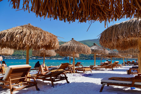 Bodrum, Turkey - August, 2020 A pearl of the Aegean sea with beaches and coasts suitable for unforgettable sea holidays. Holiday banner. Hotel Lux Lujo beach at sunrise. Bamboo parasols, azure ocean, white boats, green covered hills, white sands and blue のeditorial素材