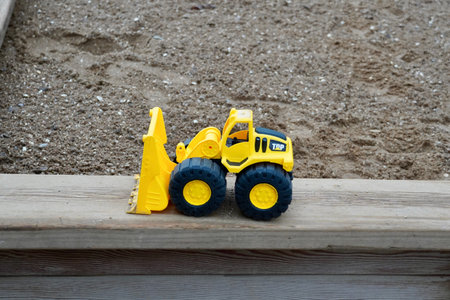 backhoe loader in yellow removing rock, car toy for kids play around outsidein the sandbox, close up carの写真素材