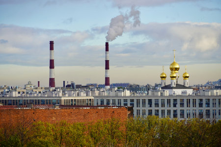 An industrial urban landscape and a steelworks with smoking pipes and a cloudy sky on the background.Urban landscape contrast - the plants pipe and the domes of the church against a beautiful sky. The photo was shot in St.Petersburg, Russiaの写真素材