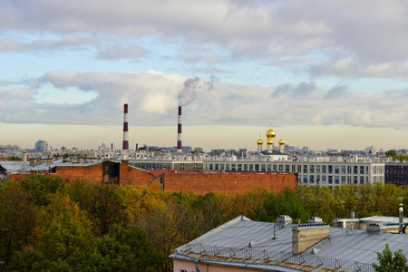 An industrial urban landscape and a steelworks with smoking pipes and a cloudy sky on the background. Urban landscape contrast - the plants pipe and the domes of the church against a beautiful sky. The photo was shot in St.Petersburg, Russiaの写真素材