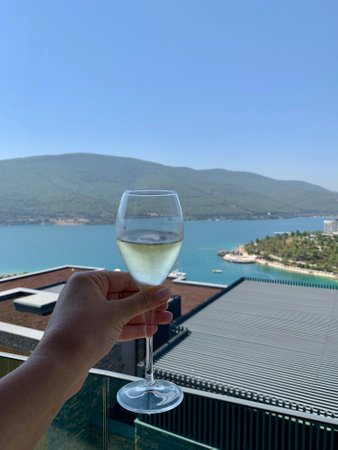 Bodrum, Turkey - August, 2020: Collection champagne MOET in a glass with bubbles in hand against the emerald Aegean Sea background. Happy lifestyleのeditorial素材