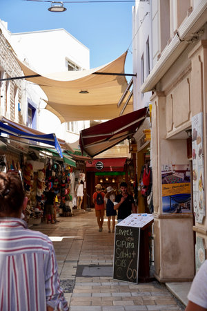Bodrum, Turkey - August, 2020: Authentic Streets of Bodrum by the Sea. Blue sky, sunshades. Crowds of tourists buy traditional Turkish souvenirs in local shops. There has been major impact worldwide in the business amid Corona Virus pandemicのeditorial素材