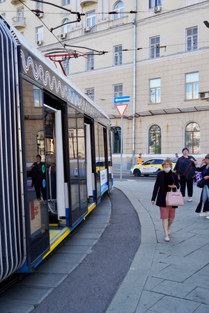 Moscow, Russia - November 2020 Photography of people at the the tram stop. People come in and out of streetcars They keep social distancing, wear and use protective face masks. Coronavirus pandemic lifestyles.のeditorial素材