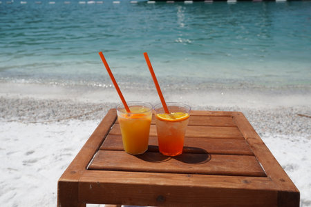 Two Orange juice, aperol spitz on wooden table on white sand beach with white boats backgrounds, Love and freedom Relax Lux vacationの写真素材