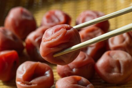 Susu,Japanese salt plums on bamboo basket. Traditional Japanese food. Close-up view.の写真素材