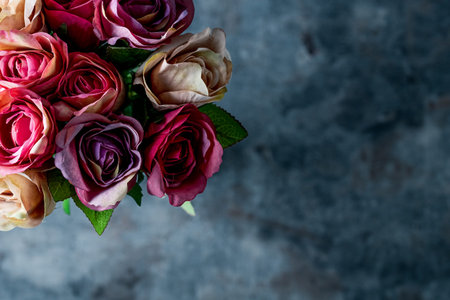 Artificial antique roses on stony background.