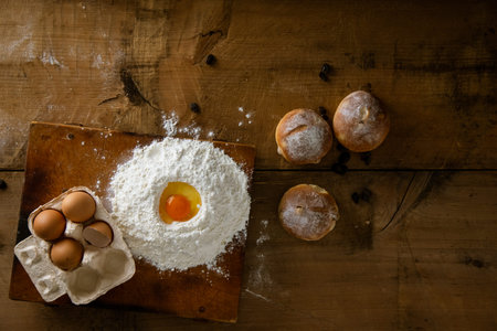 Breads and flour with some eggs. Fresh breads on wooden board background.の写真素材