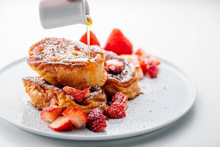 French toast with fresh strawberries and honey syrup on white plate. Delicious dessert image.の写真素材