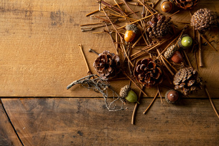 Wooden background with artificial autumn acorns, pine cones and branches.