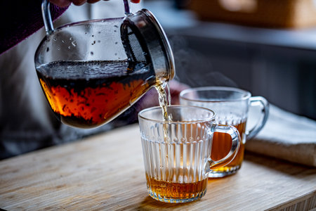 Woman is making hot tea in the kitchen.の写真素材