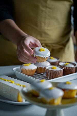 Male pastry making lemon cupcakes at table in kitchen.の写真素材