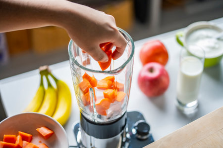 Woman hands making a healthy smoothie in the kitchen.Smoothie with bananas, carrots and tomatoes.Healthy eating concept image.の写真素材