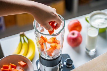 Woman hands making a healthy smoothie in the kitchen.Smoothie with bananas, carrots and tomatoes.Healthy eating concept image.の写真素材