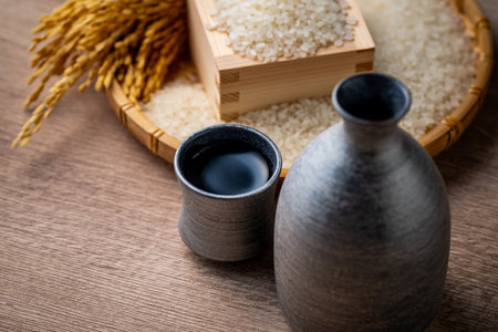 Sake and Japanese Rice A close-up of a traditional Japanese sake flask and cup with white rice and golden rice stalks in the background. This image highlights the connection betweの写真素材