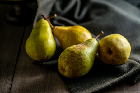 Still Life with Pears on Dark Background. A moody and rustic still life photograph featuring ripe...