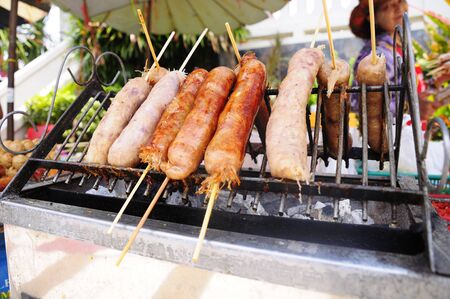 MUKDAHAN, THAILAND - APR 24, 2011 Thai Sausages are grilled on charcoal stove. Prepared for sale to tourists visiting the Indochina market. Mukdahan, Thailand.のeditorial素材