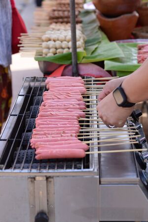 Pink hotdog Skewers Is being roasted on an electric stoveの写真素材