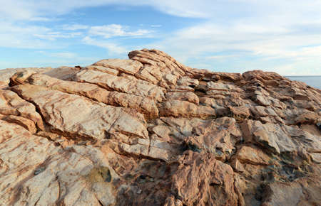The cracked brown rocks On the background is a bright sky in the afternoon. Located by the sea in the eastern part of Thailandの写真素材