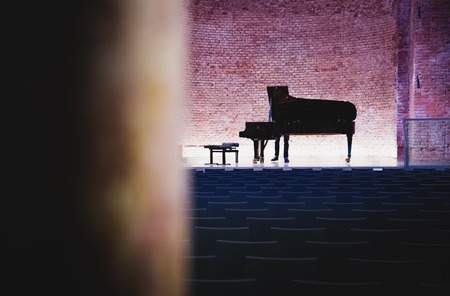 Concert grand piano in concert hall with walls of exposed red brickの写真素材