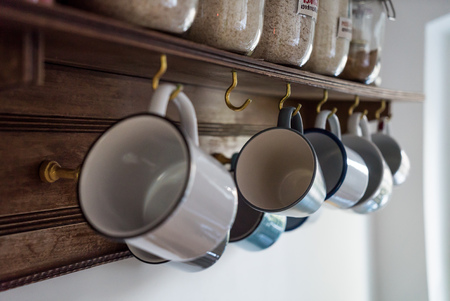 coffee cups hanging on hooks of kitchen wallの写真素材
