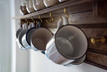 cups hanging in kitchen on wooden wallの写真素材