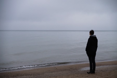 woman on the beach longing looking to the foggy misty seaの写真素材