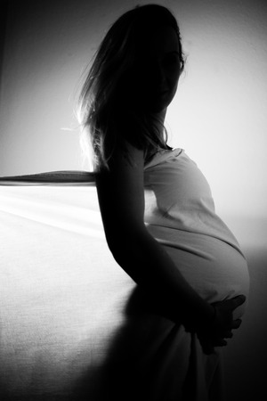 Silhouette of a pregnant woman holding her belly black and whiteの写真素材