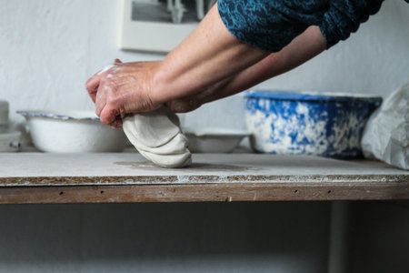 Raw clay in the hands of woman at pottery shelfの写真素材
