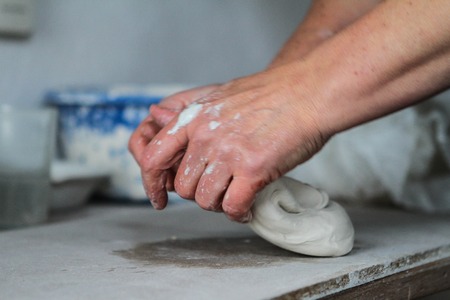 Adult female potter master preparing the clay on table. Front view, closeup, hands only, unrecognizable. Art and business, hobby and freelance working concept.の写真素材