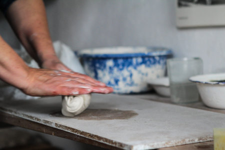Raw clay in the hands of woman at pottery shelf