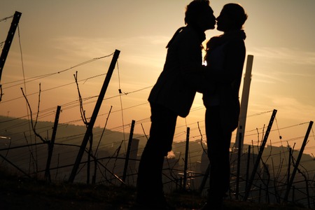 silhouette of couple kissing and standing in sunsetの写真素材