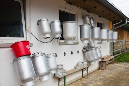 milk churns hanging outside farm for cowsの写真素材