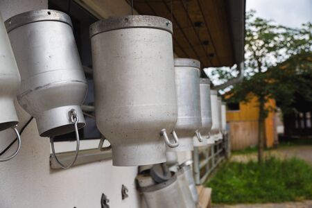milk churns hanging outside farm for cowsの写真素材