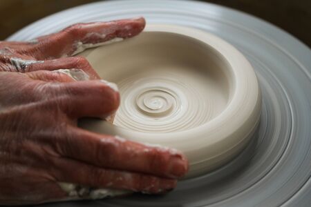 Hands of a potter, creating white porcelainの写真素材