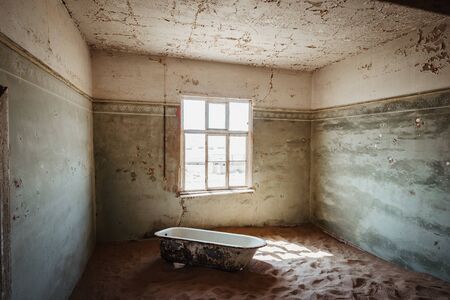 Desert sand entering old abandoned building with bath tubの写真素材